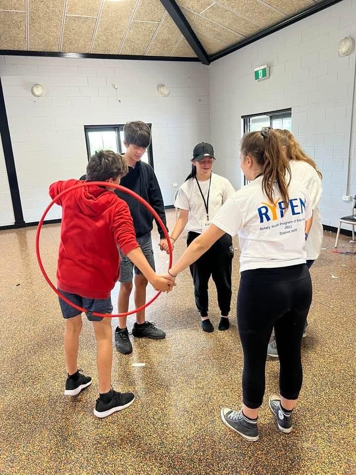 Participants passing a hoop around a linked circle at an early camp