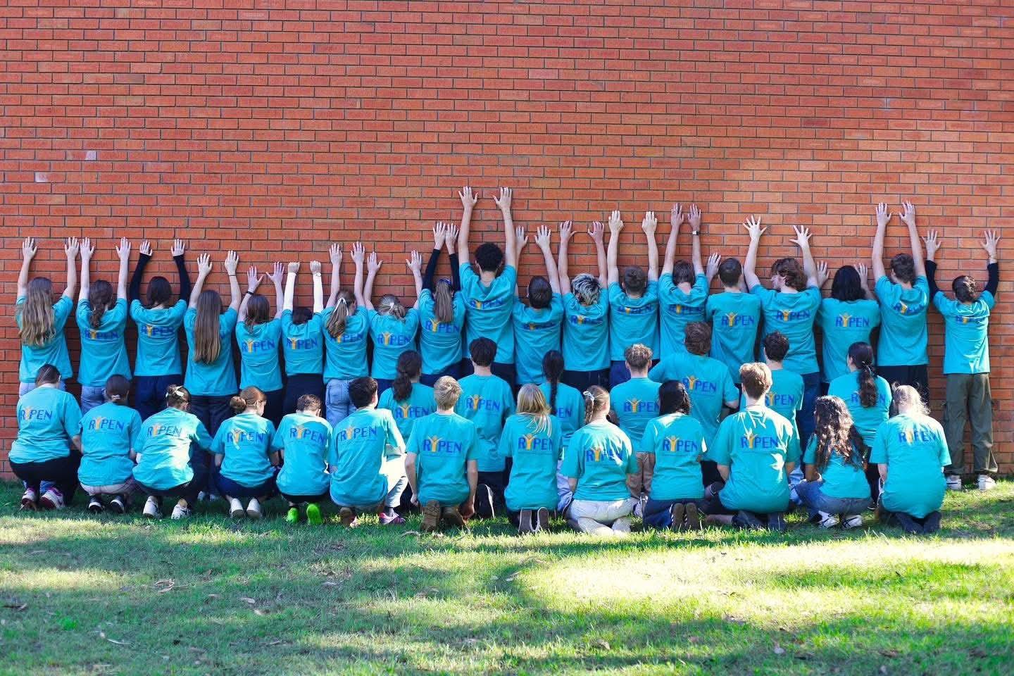 The 2023 group photographed against a brick wall