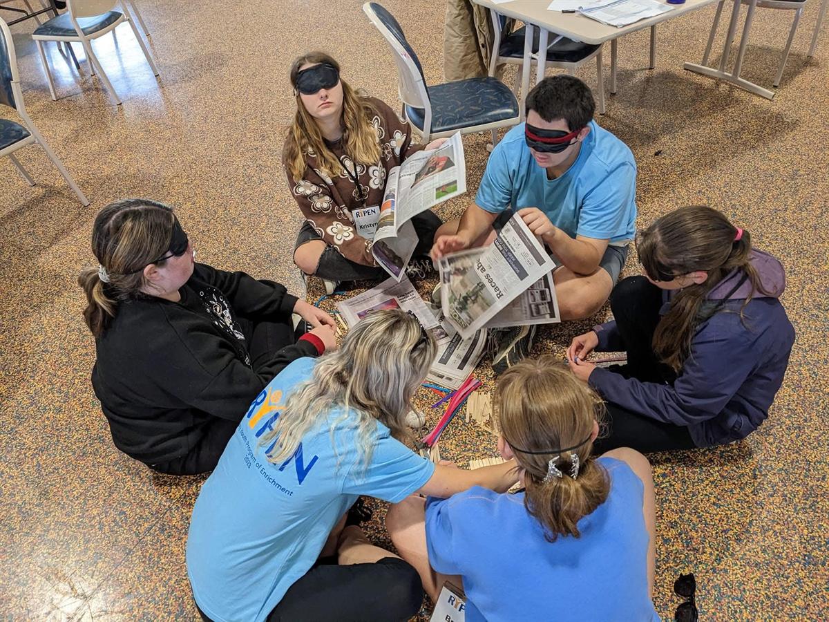 A blindfolded team activity on the floor