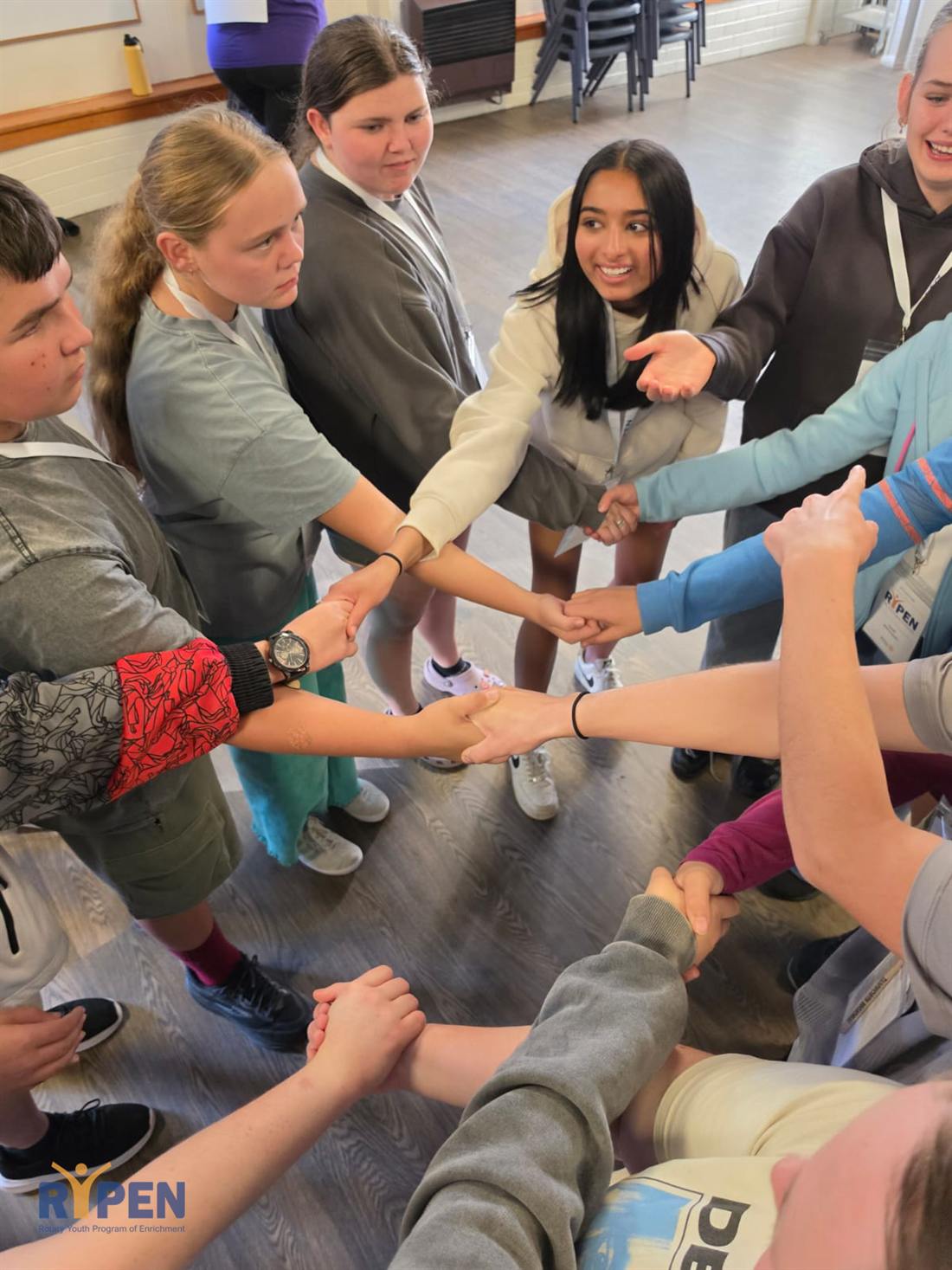 Participants reaching into the middle of a circle at the 2026 camp