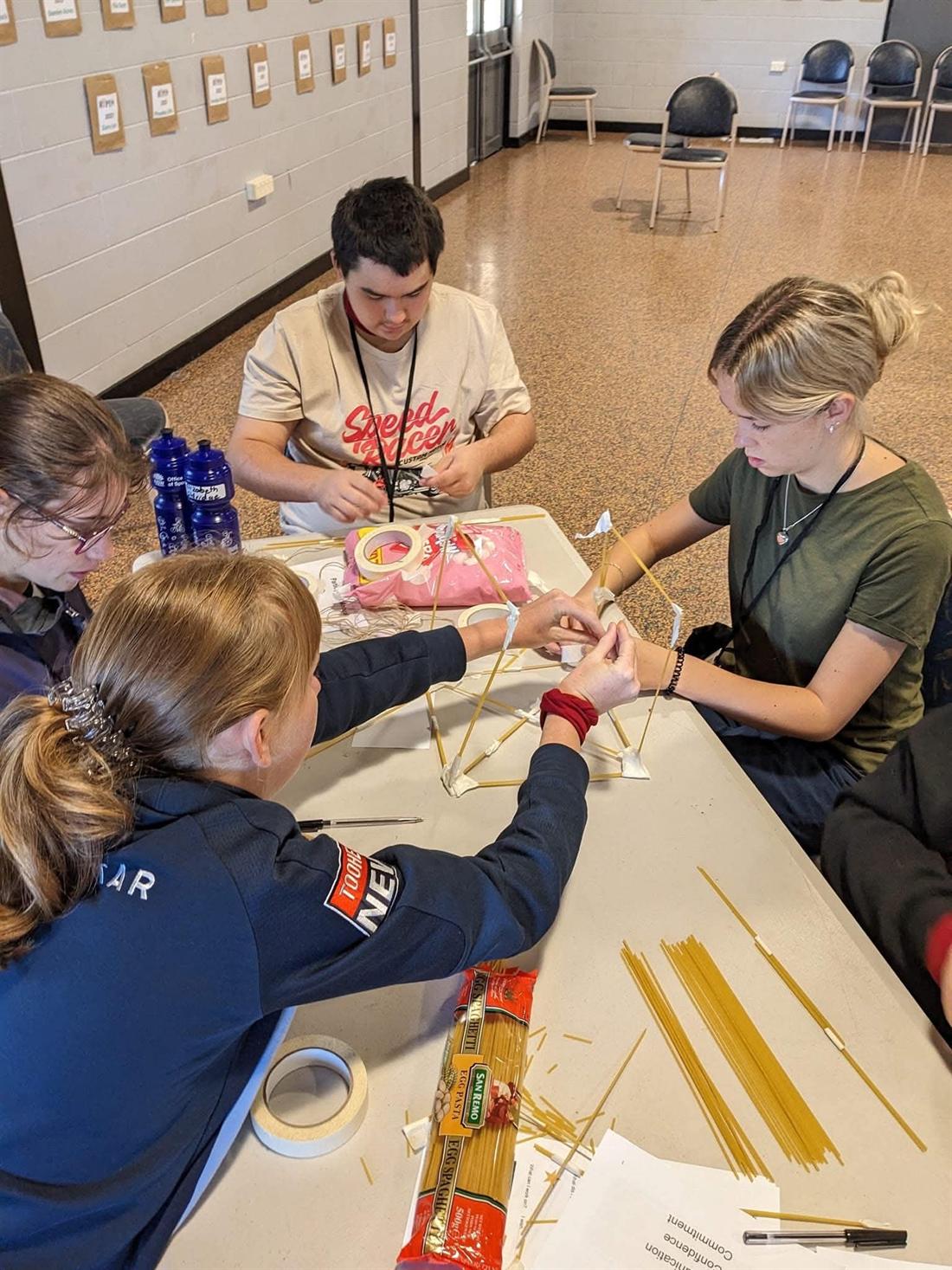 A team building a spaghetti tower together